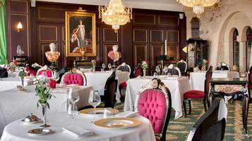Un comedor formal con mesas redondas, sillas elegantes y candelabros.