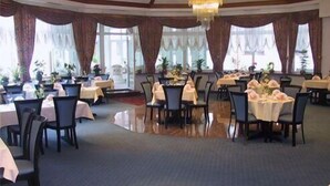 A spacious dining area with round tables, chairs, and a chandelier. - Arosa Hotel (Kassel)