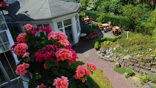 A garden with a gazebo, a brick pathway, and outdoor seating. - Arosa Hotel (Kassel)