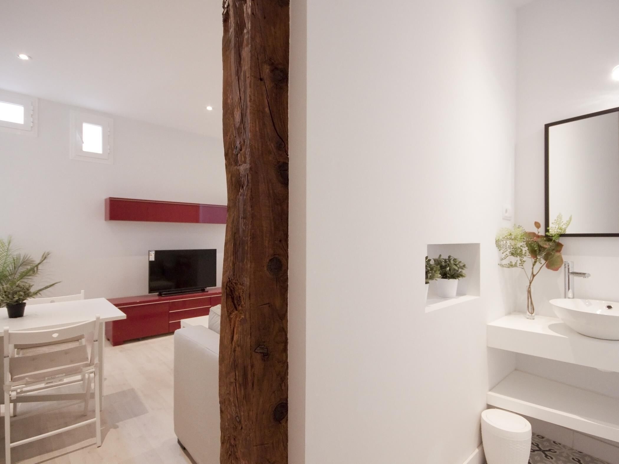 Une salle de bain moderne avec un grand miroir, un lavabo blanc et un élément décoratif en bois.