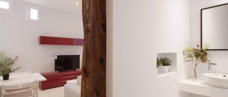 Une salle de bain moderne avec un grand miroir, un lavabo blanc et un élément décoratif en bois.