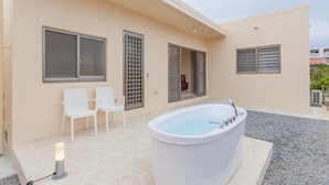 Ein Wellnessbereich mit Whirlpool, zwei weißen Sesseln und einem kleinen Tisch.