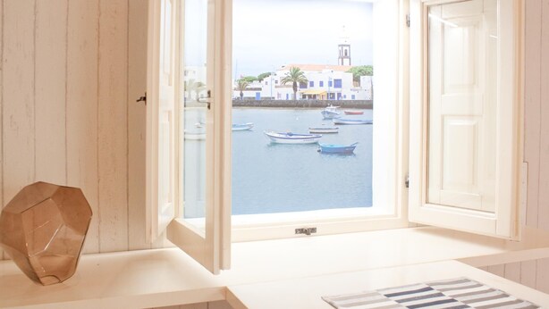 Una habitación con un amplio ventanal con vista a un puerto con barcos y edificios.