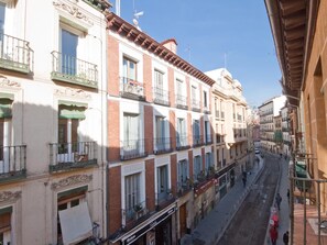 A narrow street lined with multi-story buildings featuring balconies and storefronts. - CAVA ALTA Charming cozy LaLatina (Madrid)