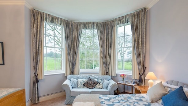 A bedroom with a bed, a sofa, and a window with curtains. - Marshwood Farm B&B (Salisbury)