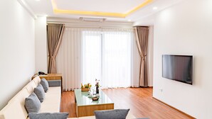 A modern living room with a sofa, a coffee table, and a TV mounted on the wall. - Draco QK3 Cat Ba (Hai Phong)