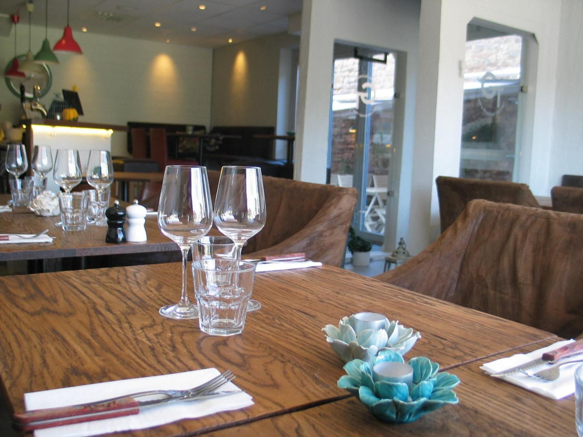 Een gedekte restauranttafel met wijnglazen en een kandelaar.