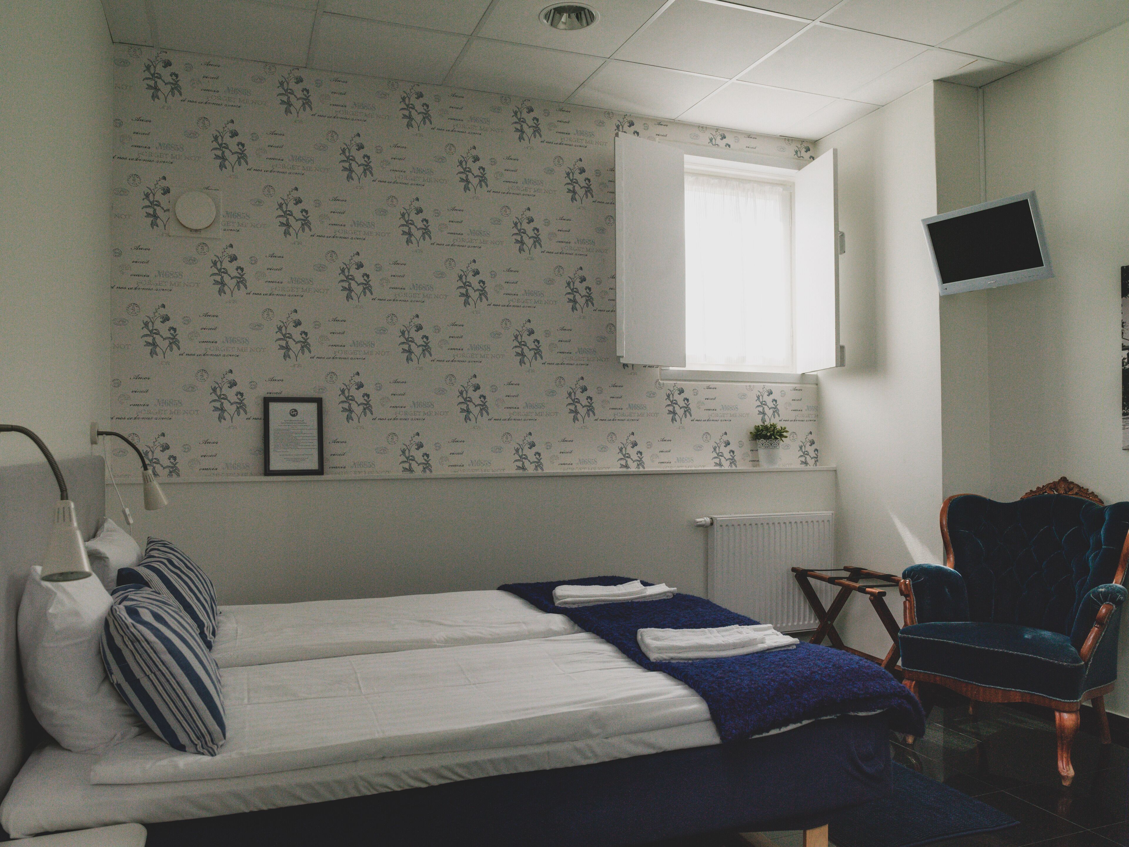 A hotel room with two beds, a small table, a chair, a TV, and a window with a curtain.