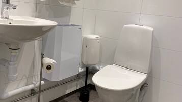 Et moderne badeværelse med hvid vask, toilet og håndtørrer.