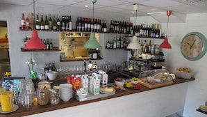 A bar area with shelves of wine bottles, a clock, and various food and drink items.