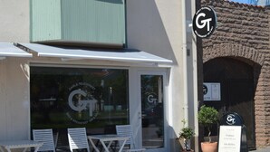 A café with a glass storefront, outdoor seating, and a signboard.