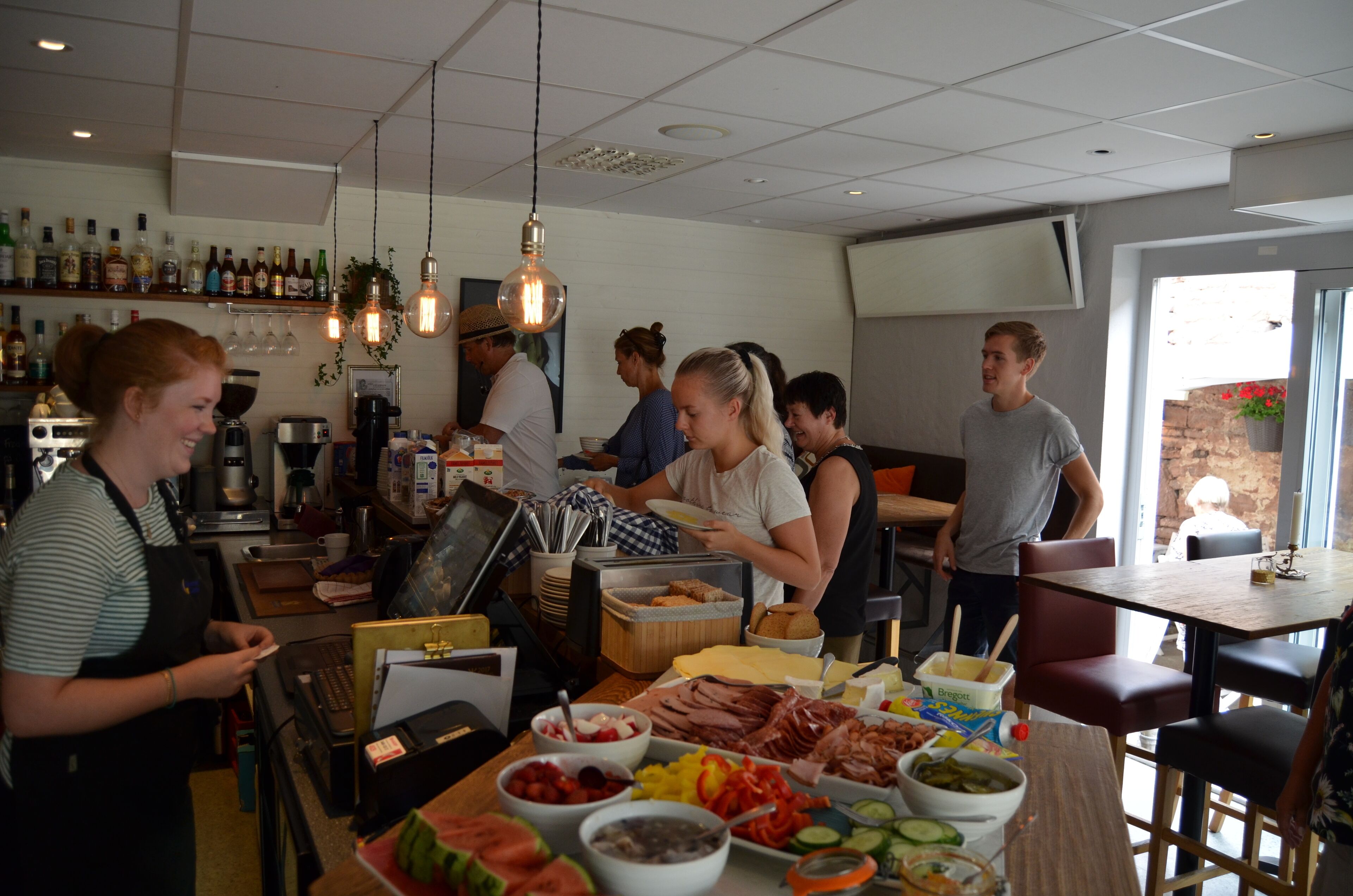 A restaurant with a bar area, a buffet with various food items, and a seating area with tables and chairs.