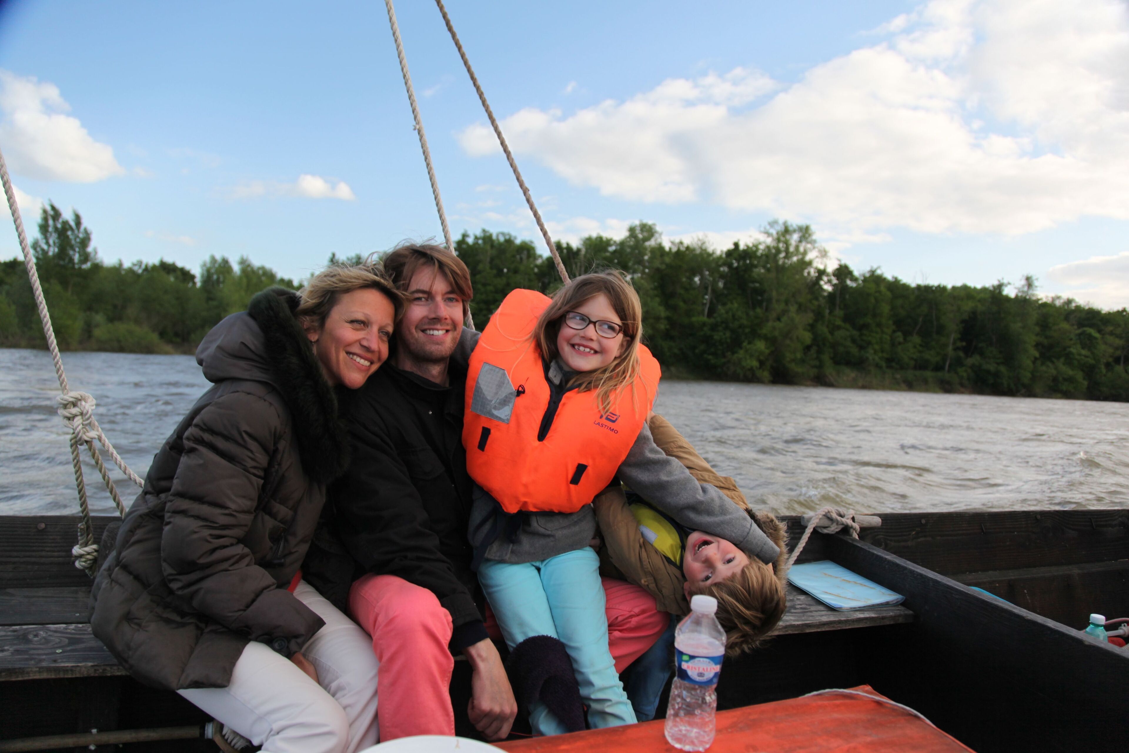 A group of people on a boat with a rope and a bottle of water visible.