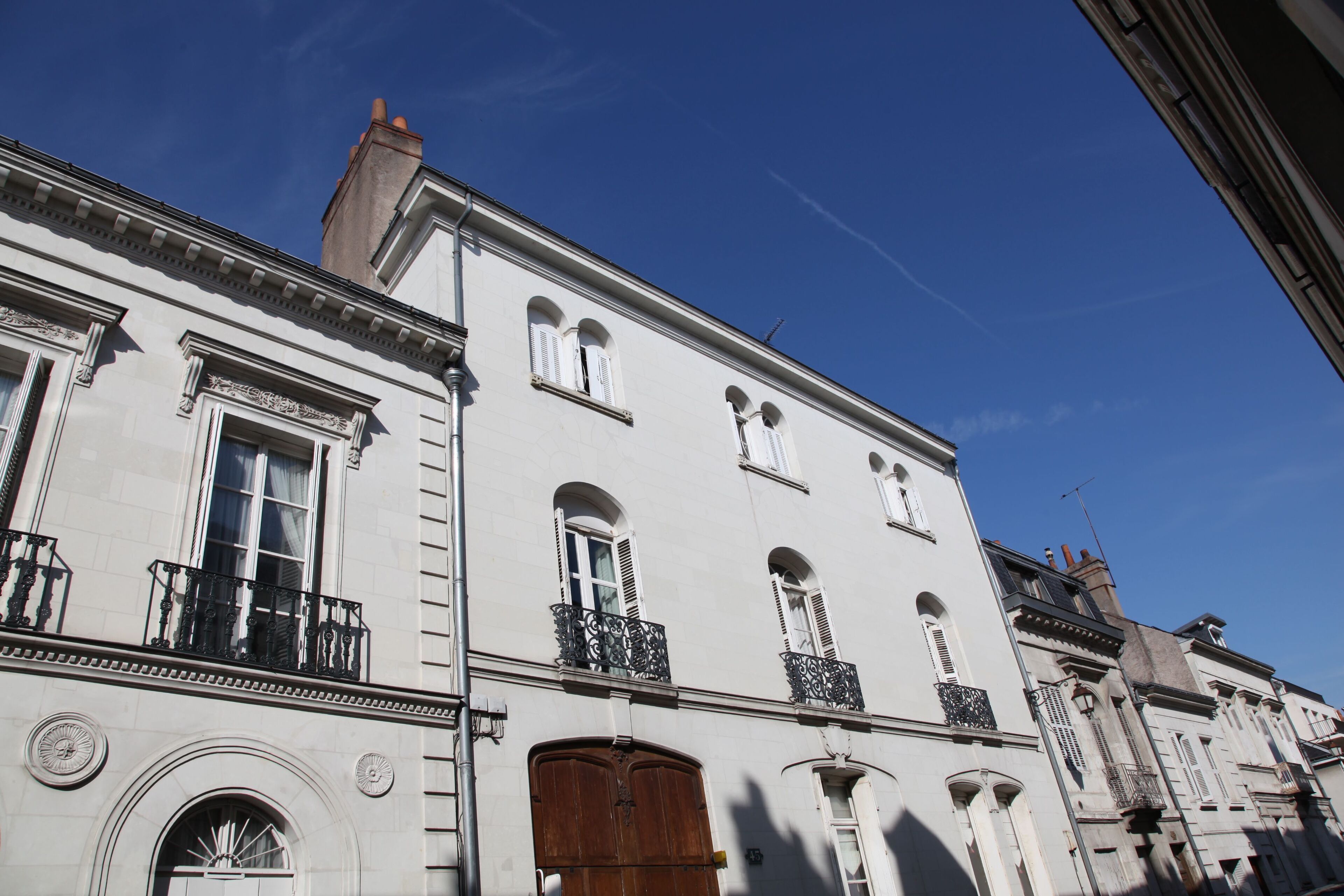 A classical building with arched windows, a wooden door, and decorative iron railings.