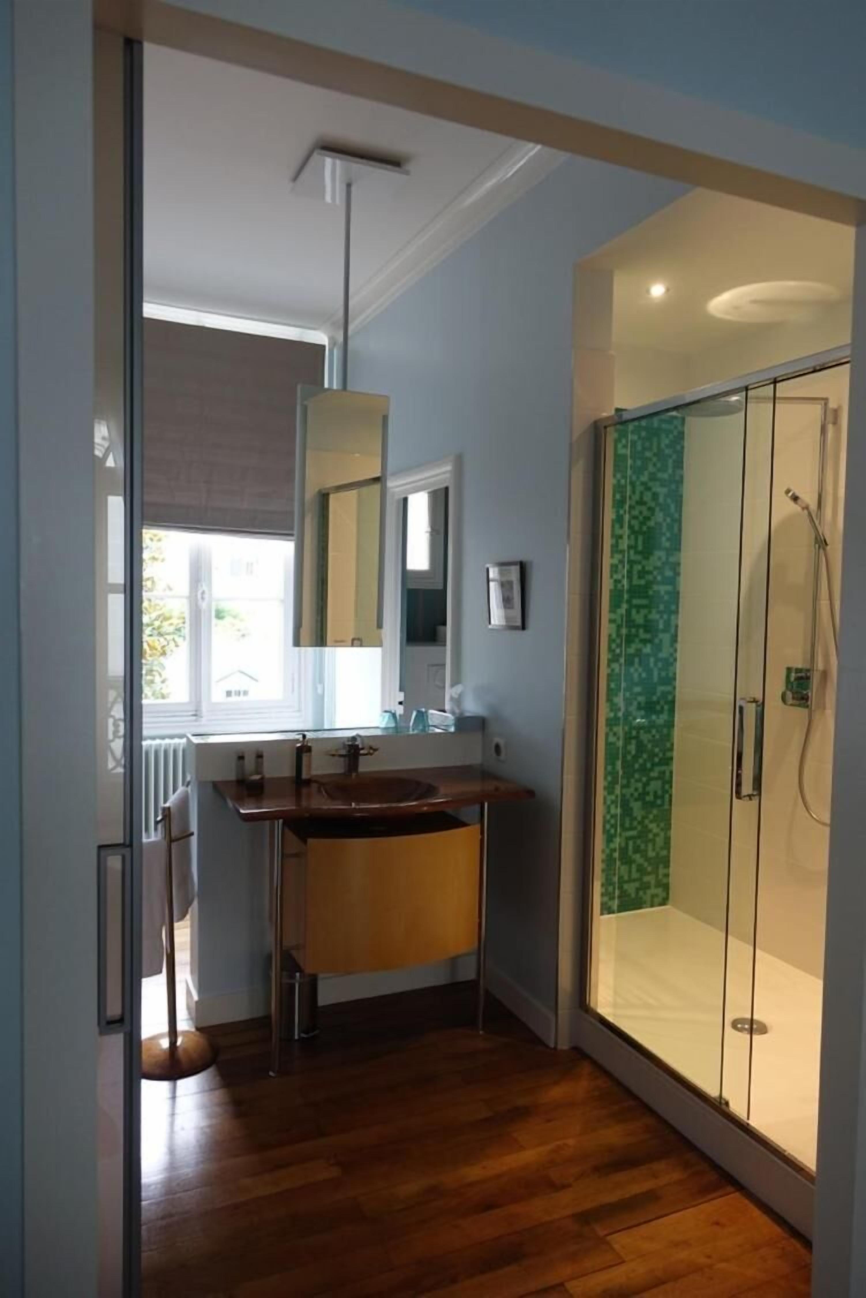 Une salle de bain moderne avec un meuble-lavabo en bois, une cabine de douche en verre et un grand miroir.