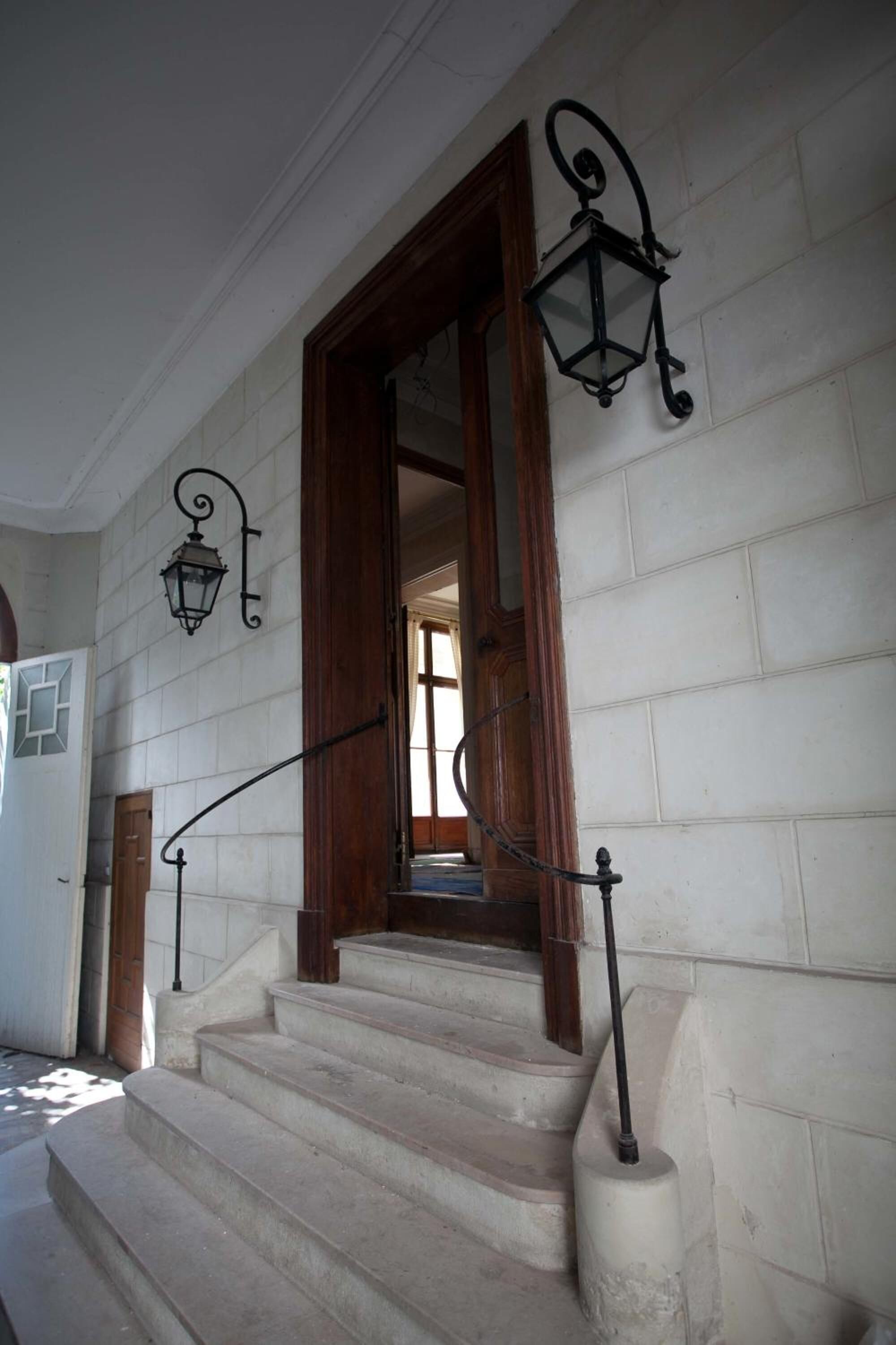 A staircase with white stone steps and black metal railings, leading to a wooden door.