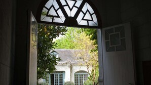 Une cour dallée de pierres menant à un bâtiment doté d’une grande entrée en arc de cercle.