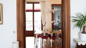 Un espace repas doté d’un plancher en bois, d’un lustre et offrant une vue sur l’extérieur grâce à une porte vitrée.