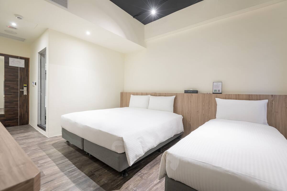 A hotel room with two beds, a wooden headboard, and a small desk.