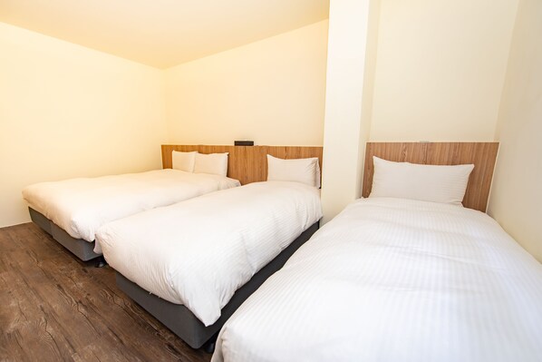 Une chambre d’hôtel avec deux lits simples, des têtes de lit en bois et un plancher en bois.