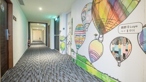 A hallway with a patterned carpet, a wall mural with hot air balloons, and a door labeled "307". - Traveller Inn Rail Haus (Taitung)