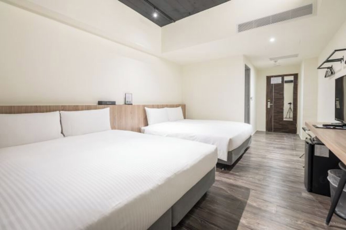 A hotel room with two beds, a desk, and a wardrobe.