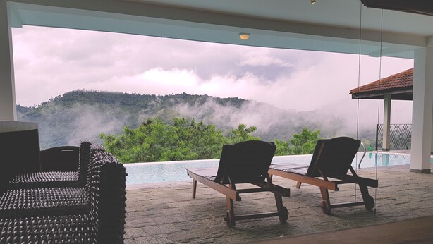 A room with a view of a mountain and a pool. There are two wooden chairs and a woven chair. - Levita (Maberiyatenna)