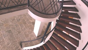 A spiral staircase with a metal railing and a white base, leading to a higher floor. - Levita (Maberiyatenna)