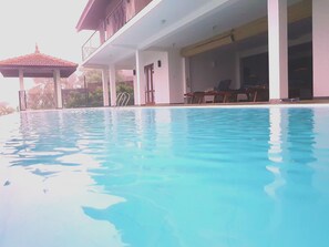 A swimming pool with a covered area and lounge chairs.