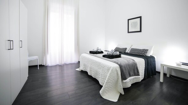 A modern bedroom with a bed, bedside table, and a chair. - Amazing Politeama house (Palermo)