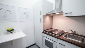 A modern kitchen with white cabinets, a stainless steel sink, and a built-in oven. - Amazing Politeama house (Palermo)