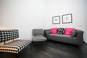 A modern living room with a grey sofa, black and white checkered bench, and matching armchair.