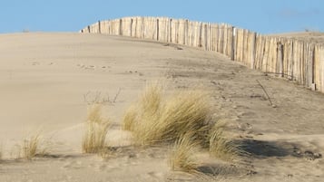 Paisaje de dunas arenosas con una valla de madera a lo largo de la cima.
