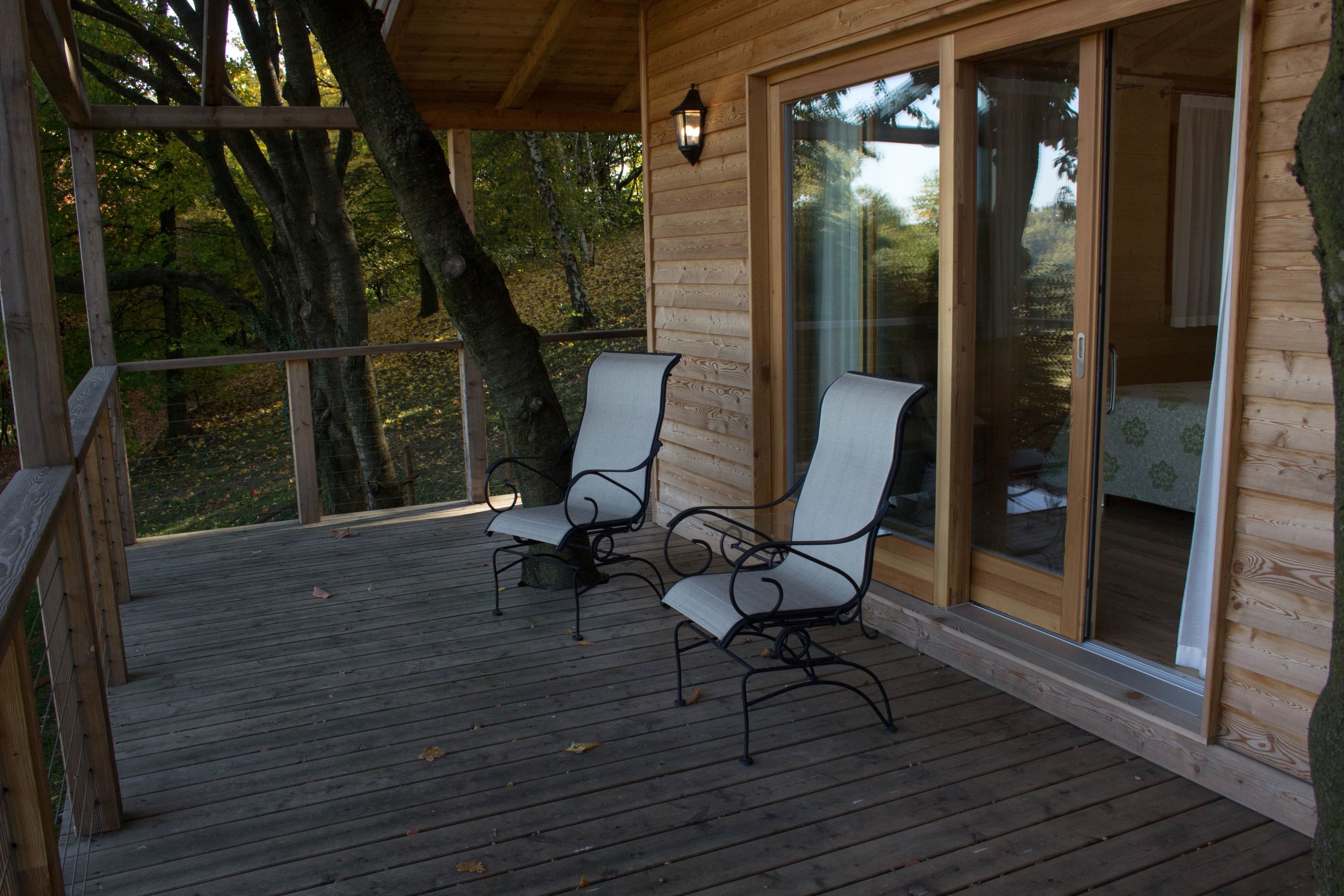 Une terrasse en bois avec deux chaises et une porte vitrée donnant sur une pièce.