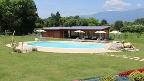 Zona de piscina con una casa, mobiliario exterior y vistas a montañas.