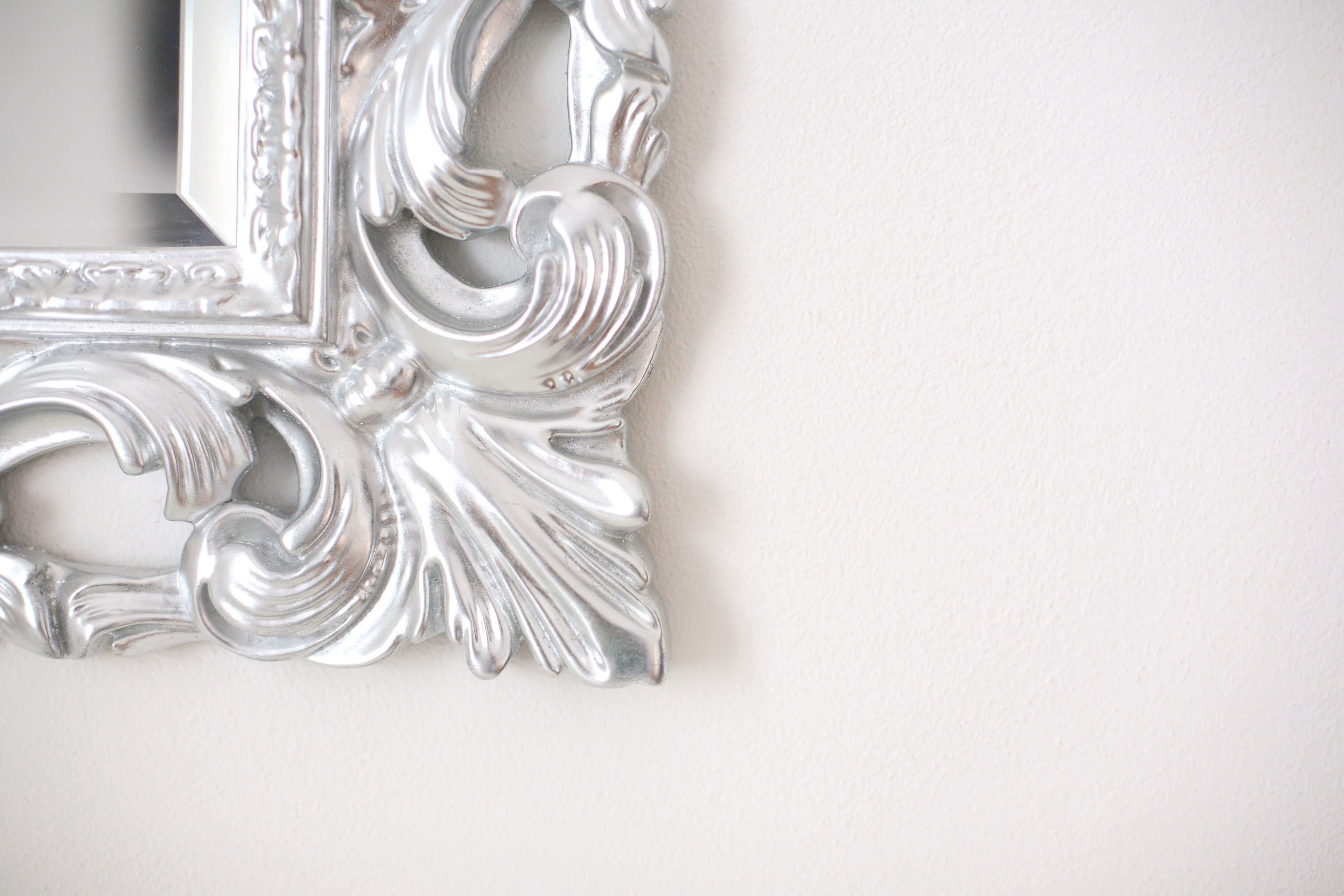 A close-up of a silver, ornate picture frame with intricate designs.