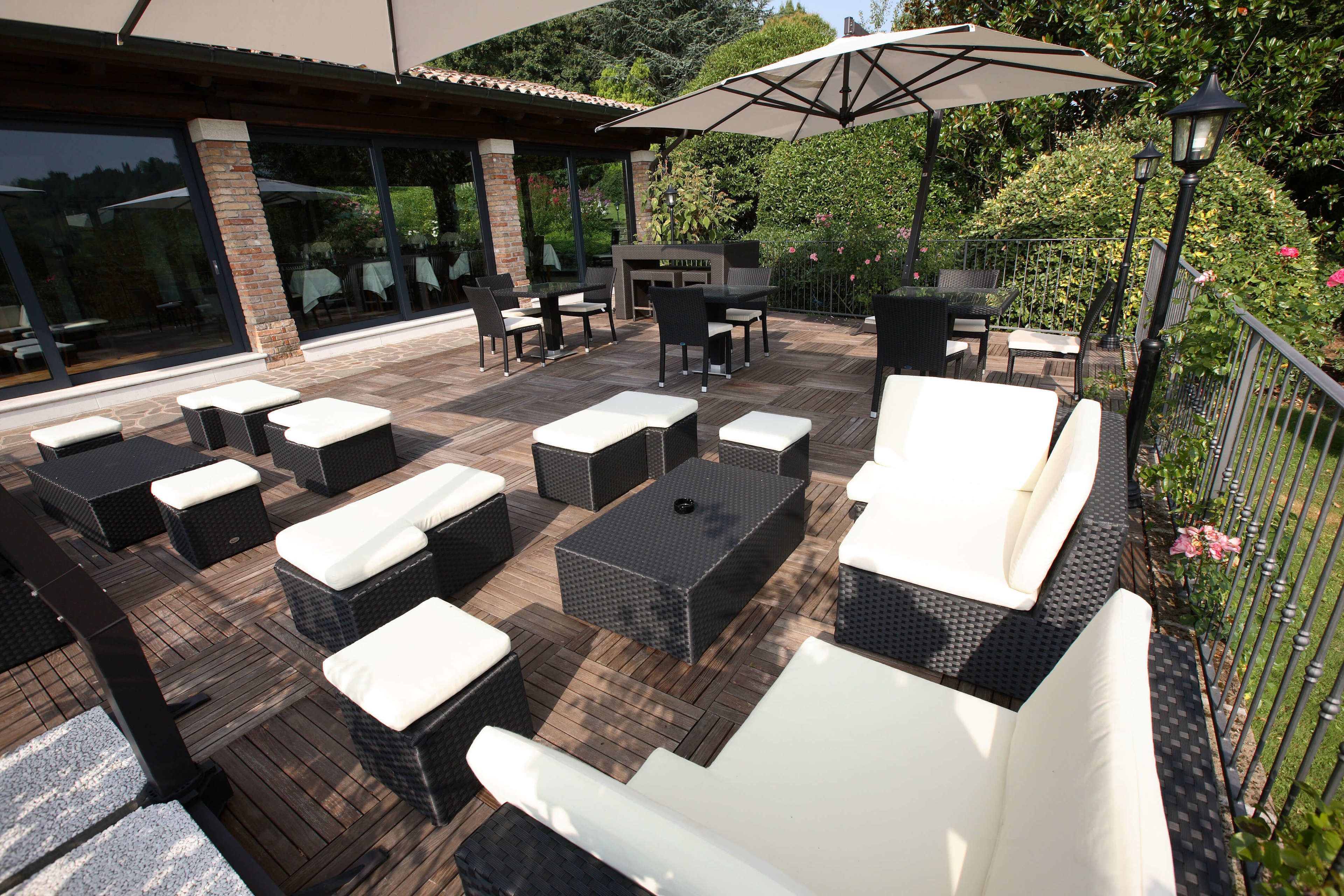 Eine Terrasse im Freien mit Korbmöbeln, einem Tisch und einem großen Sonnenschirm.