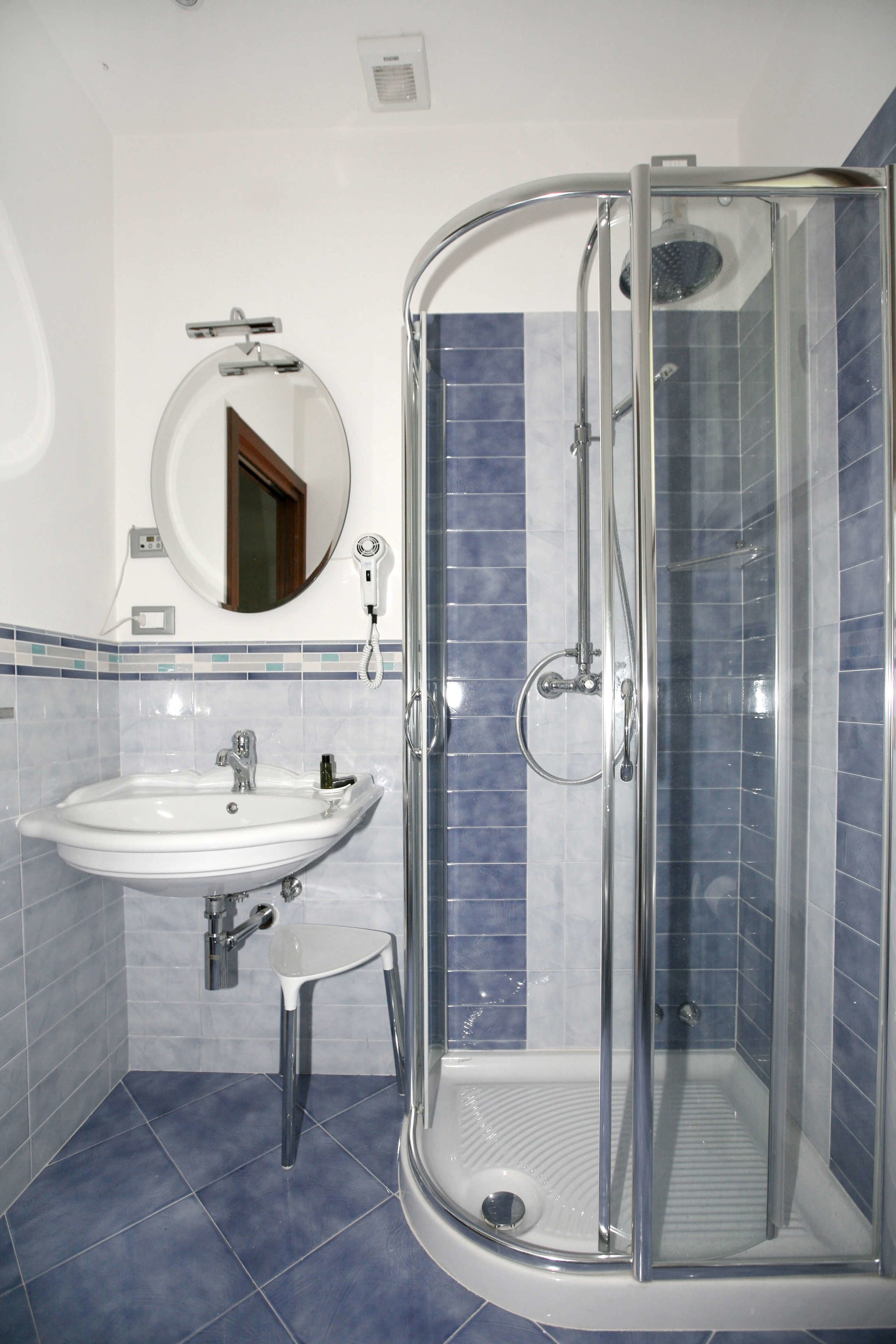 A bathroom with a glass-enclosed shower, a sink, and a mirror.