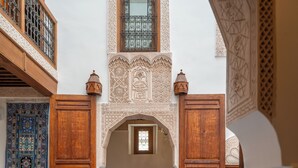 Un interior tradicional marroquí con detalles de azulejos intrincados, muebles de madera y una zona de estar central.