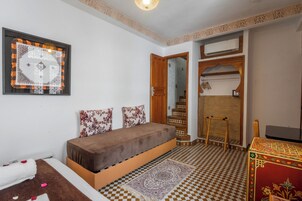 Un dormitorio con una cama, un armario de madera, un espejo y un tapete estampado.
