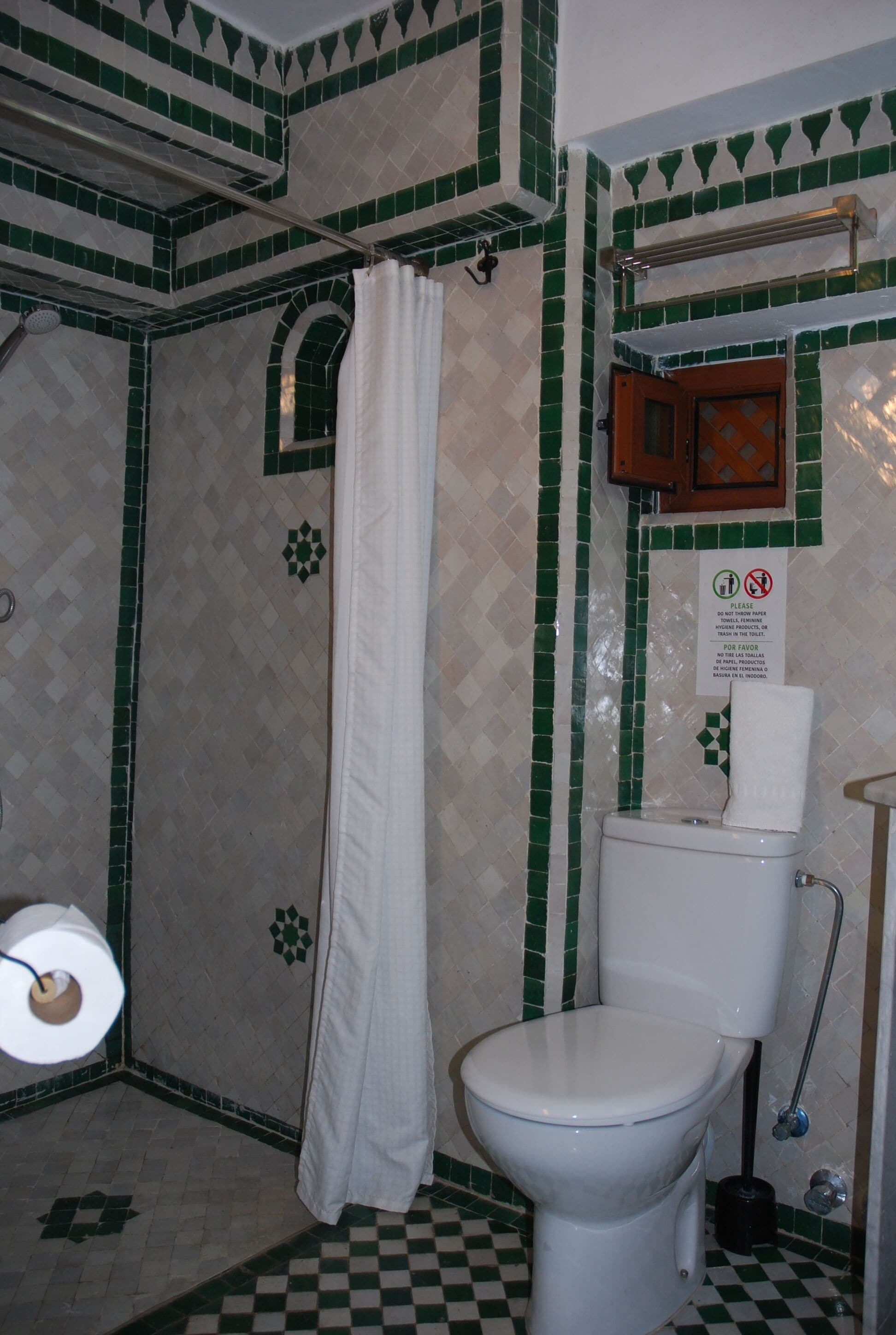 Un baño con inodoro, cortina de ducha y paredes de cerámica.
