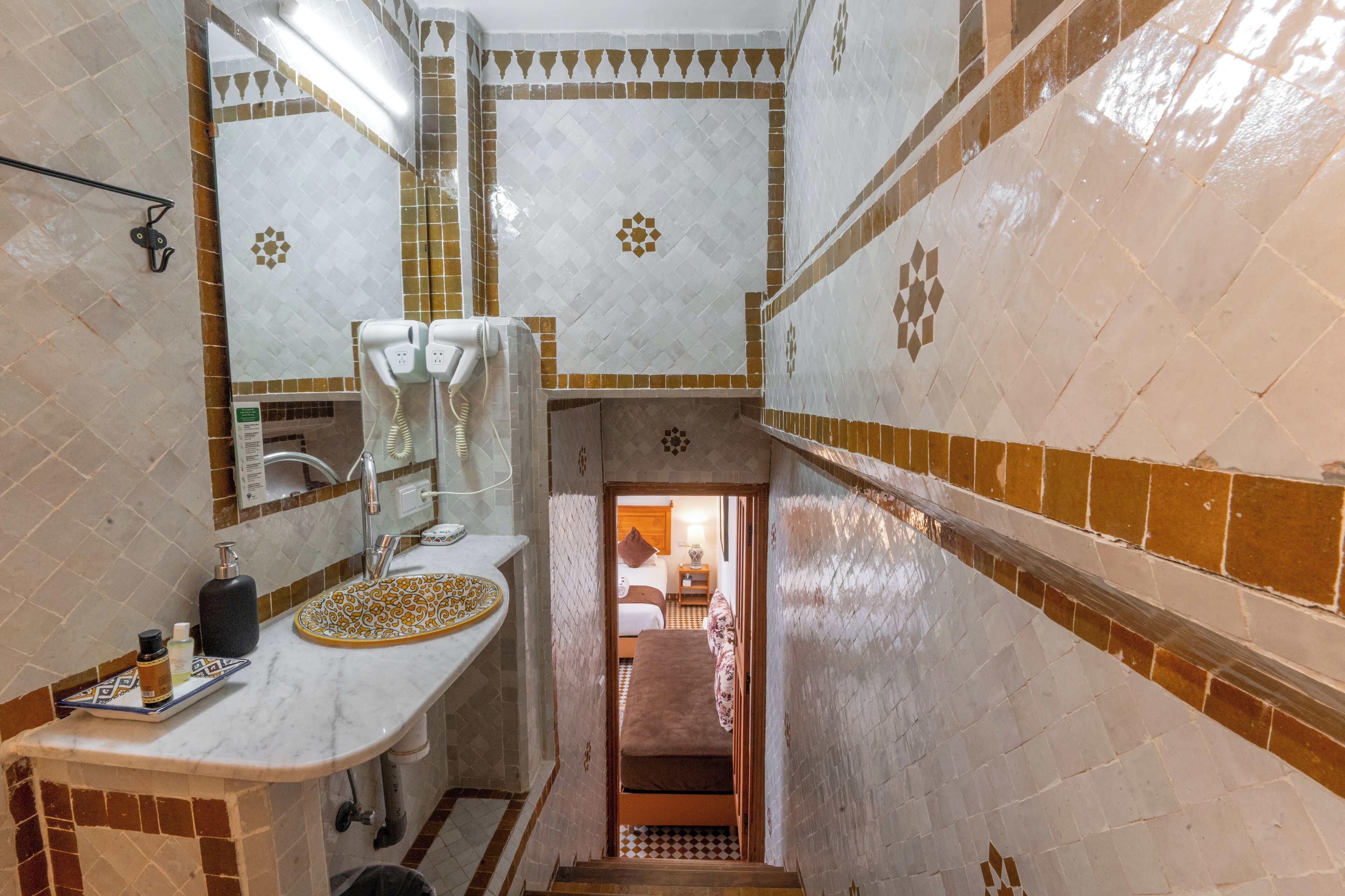 Un bany amb un lavabo blanc, un mirall i rajoles amb dibuixos.