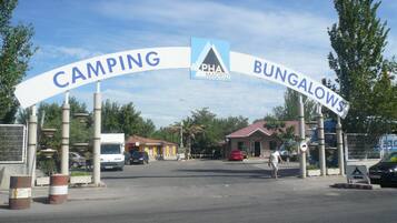 Camino que lleva a una zona de camping y bungalows, con un cartel que indica la dirección.