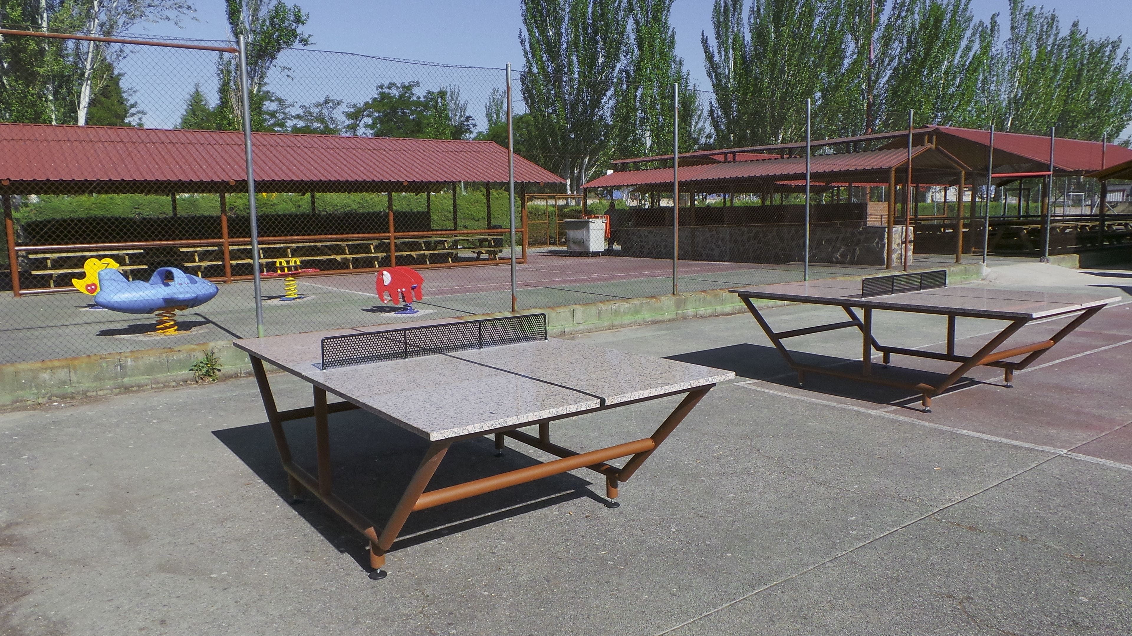 Un espacio al aire libre cubierto con mesas de picnic y juegos infantiles.