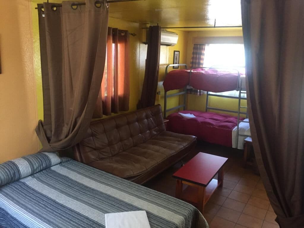 Una habitación con una cama, un sofá, una mesita y una litera.