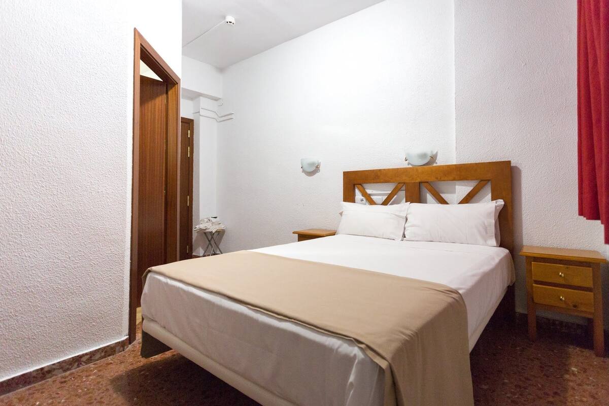 A bedroom with a bed, bedside tables, and a wardrobe.