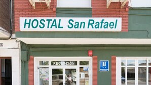 Un edificio con un cartel que dice "HOSTAL San Rafael" y una zona de recepción con acceso para sillas de ruedas.