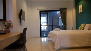 A hotel room with a bed, a desk, a chair, a TV, and a balcony with a view. - Sabai @ Chumphae (Chum Phae)