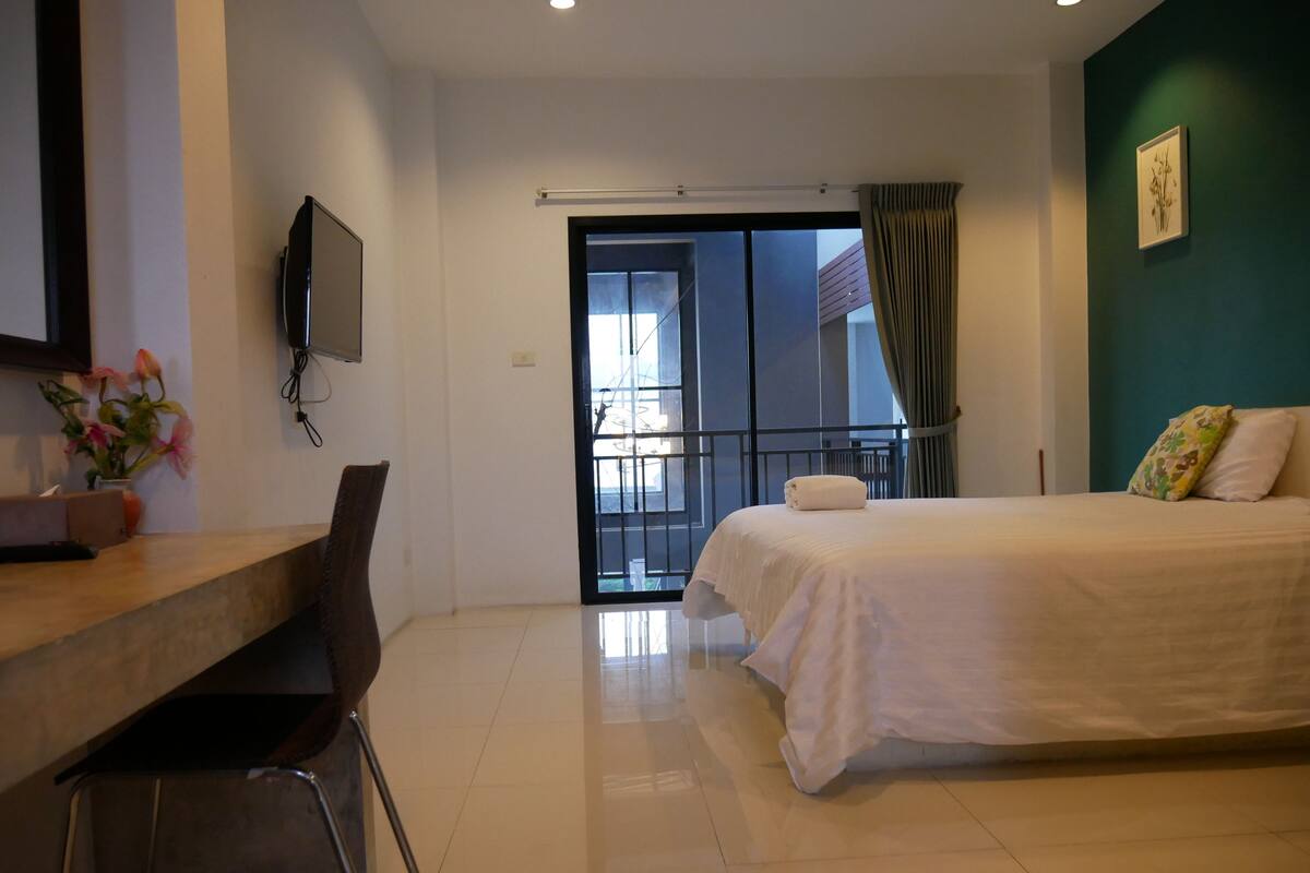 Ein Hotelzimmer mit Bett, Schreibtisch, Sessel, Fernseher und einem Balkon mit Blick.