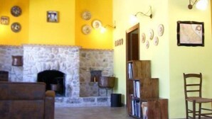 Un interior rústico con chimenea de piedra, vigas de madera y una pared amarilla.